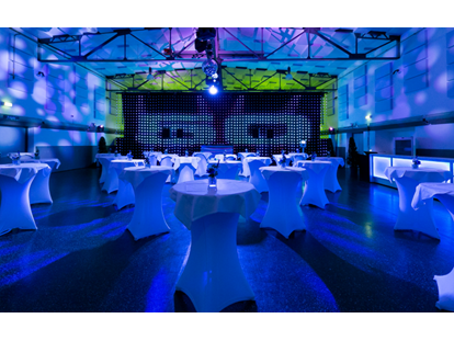 Tagungshotels - Garderobe - Markthalle mit Bühne & LED-Wall + Ambientelicht mit Projektionen + hauseigenen runden Stehtischen mit Hussen + beleuchteten Bars - Seifenfabrik Veranstaltungszentrum