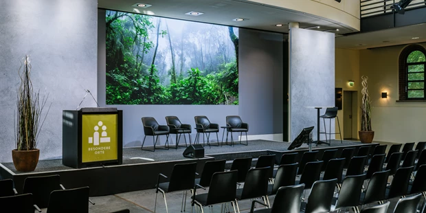 Tagungshotels - Beamer und Leinwand - Seitliche Ansicht auf die bestuhlte Bühne mit moderner LED Wall - Umweltforum
